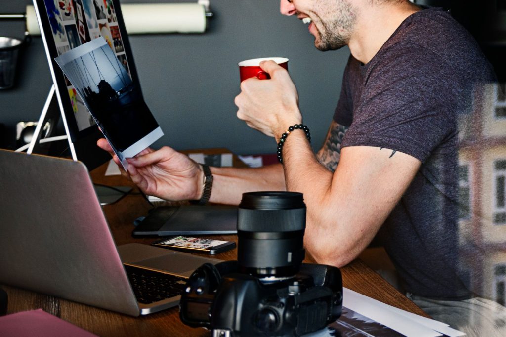 Mężczyzna siedzący przy biurku z laptopem i popijający filiżankę kawy podczas pracy nad pojedynczym postem nr 734 przy użyciu Elementora.