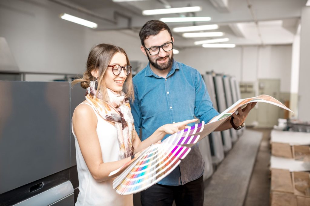 Mężczyzna i kobieta patrzą na kartę kolorów w drukarni Druk.