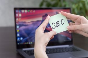 Ręce trzymające karteczkę z napisem "SEO" - Pozycjonowanie strony w Niemczech